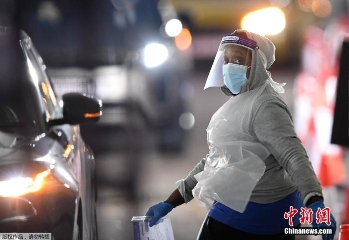 當?shù)貢r間12月18日，英國政府公布的數(shù)據(jù)顯示，當天英國新增奧密克戎毒株感染病例10059例。鑒于奧密克戎毒株感染病例激增，住院人數(shù)不斷上升，倫敦市長宣布倫敦進入“重大事故”狀態(tài)。圖為倫敦的一個免下車檢測中心，一名醫(yī)務(wù)工作者正準備對司機進行核酸檢測。