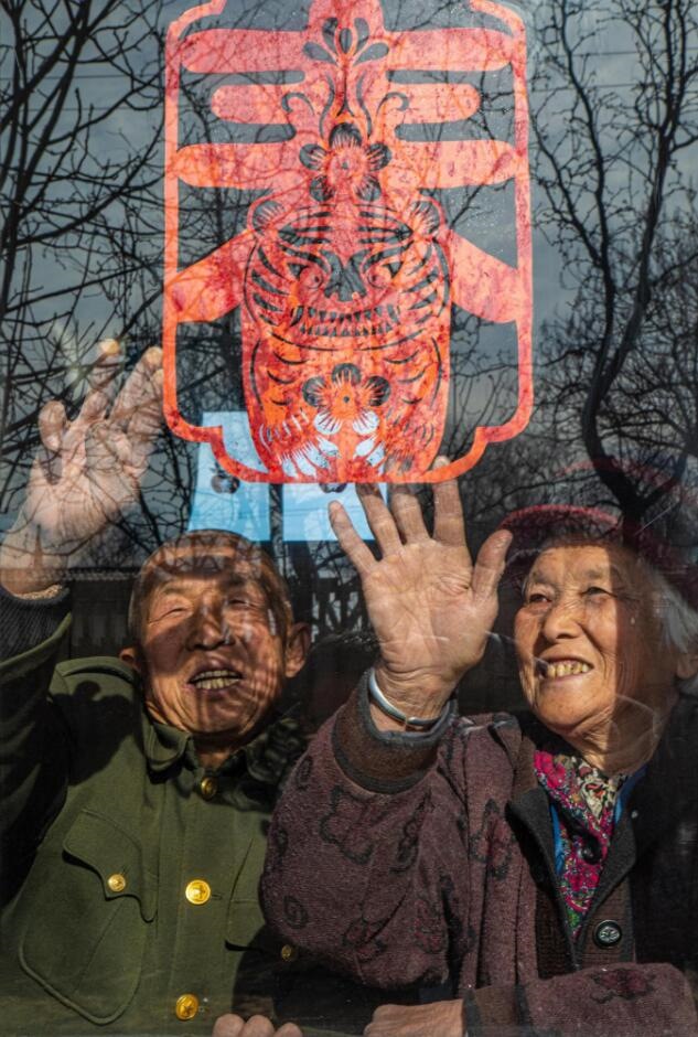 臘月里，霍州市師莊鄉(xiāng)馮南垣村村民師榮光(左)在災(zāi)后重建的新家里貼窗花。(霍州市委宣傳部供圖)