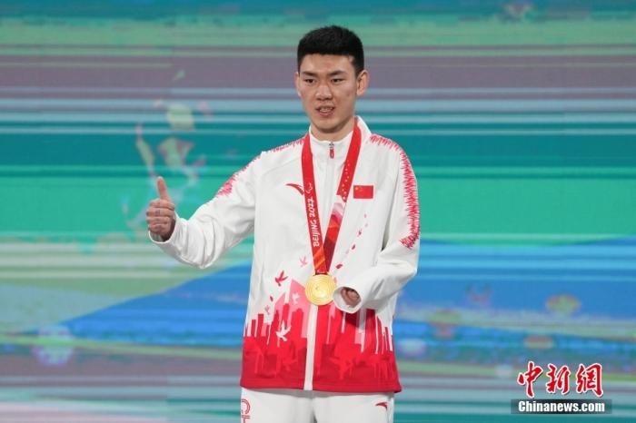 3月6日，梁景怡在延慶頒獎廣場領獎臺上豎起大拇指。當日，在國家高山滑雪中心舉行的北京2022年冬殘奧會殘奧高山滑雪男子超級大回轉—站姿決賽中，中國選手梁景怡奪得冠軍。 <a target='_blank' href='/'>中新社</a>記者 楊華峰 攝