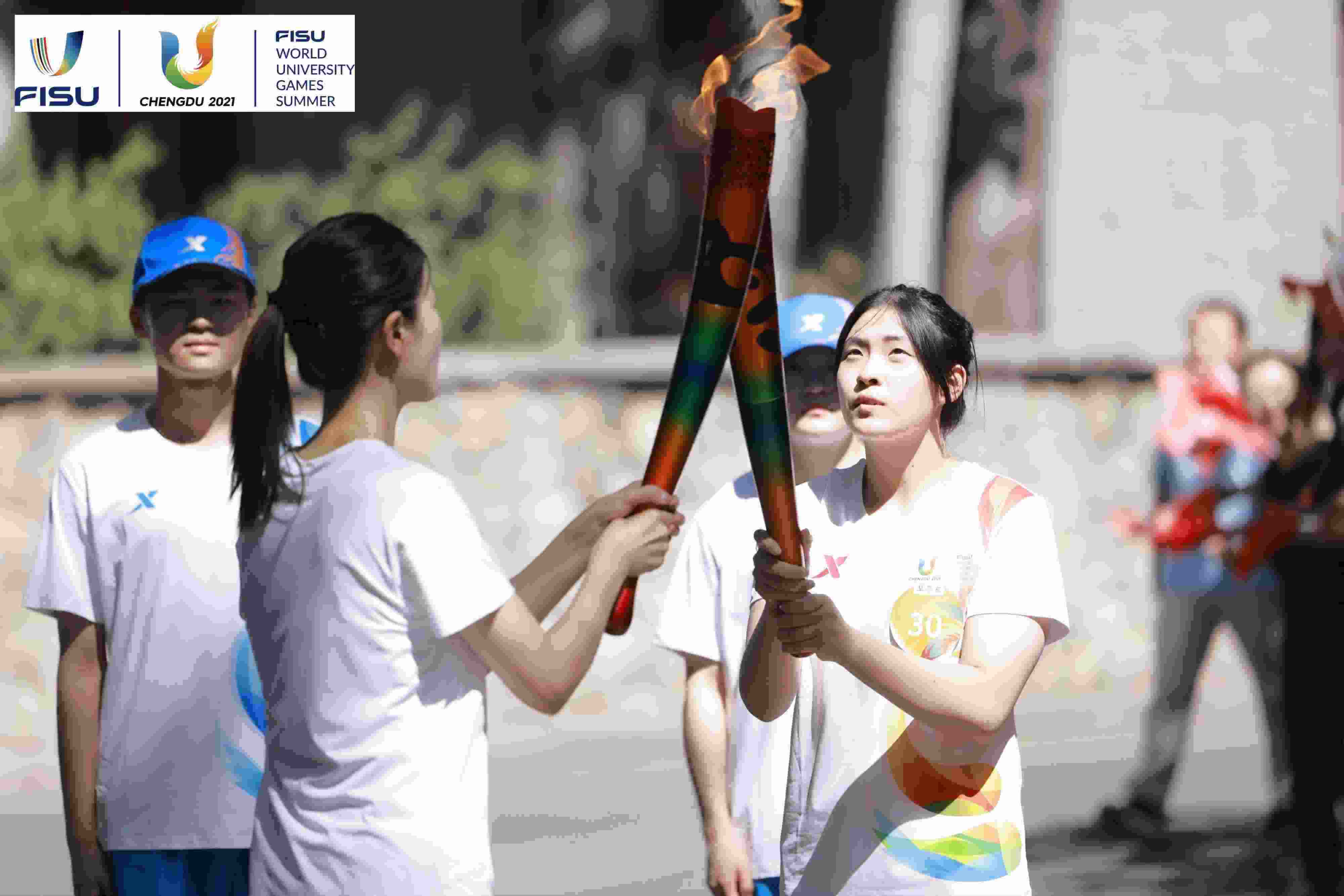 兩名大運(yùn)會火炬手進(jìn)行火炬?zhèn)鬟f。 圖片來源：成都大運(yùn)會執(zhí)委會供圖