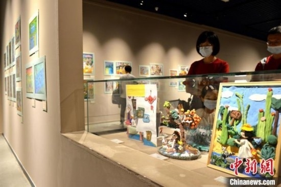 圖為家長(zhǎng)帶著孩子參觀展覽。呂明 攝