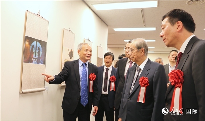 “湖州印象”攝影展主創(chuàng)、世界華人攝影協(xié)會(huì)副會(huì)長(zhǎng)馮學(xué)敏向吳江浩大使、福田康夫前首相等嘉賓介紹展出作品。（人民網(wǎng) 許可攝）