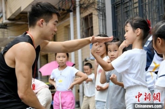 圖為大學(xué)生志愿者在組織孩子們參加體育健身活動。廖光福 攝