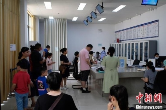 圖為在戶籍辦證廳內(nèi)排隊等待的家長和孩子。劉俊聰 攝