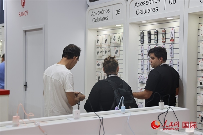 幾名參觀者在一個(gè)展臺(tái)前了解手機(jī)配件。（人民網(wǎng)記者 時(shí)元皓攝）