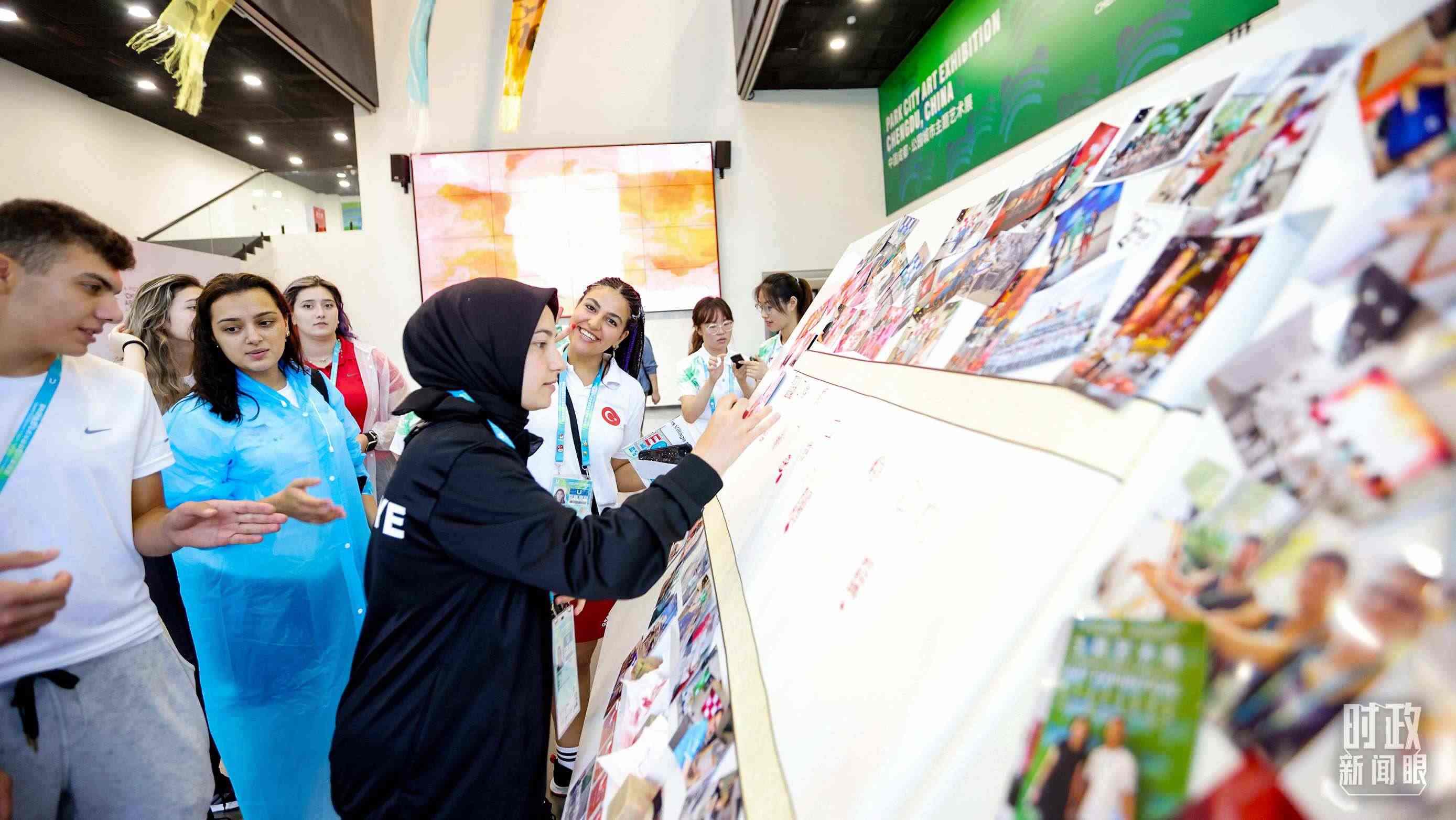 各國(guó)青年運(yùn)動(dòng)員正在參觀成都大運(yùn)村內(nèi)的“雪山下的公園城市，煙火里的幸福成都”主題藝術(shù)展。（總臺(tái)央視記者魏幫軍拍攝）