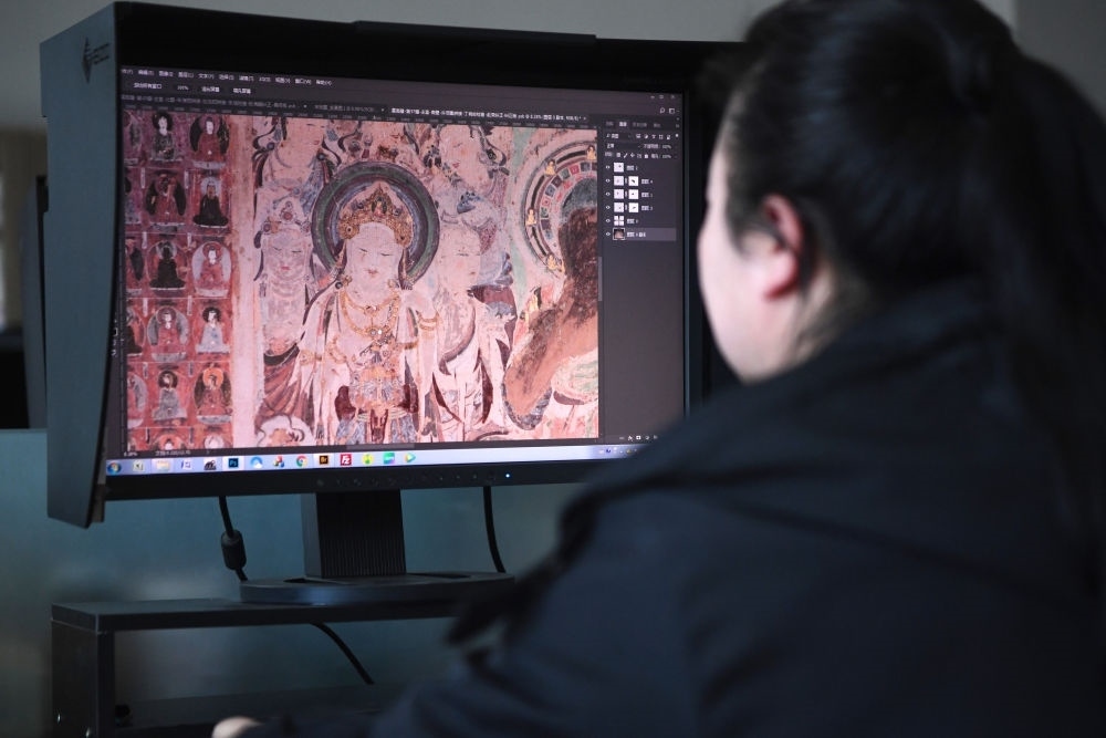 敦煌研究院文物數(shù)字化保護團隊圖像處理人員年海麗在拼接壁畫圖像（2023年4月25日攝）。數(shù)字化探索為莫高窟的保護與傳承開辟了全新路徑，數(shù)字技術讓敦煌文物走出洞窟，跨出國門，走向“永久保存、永續(xù)利用”。新華社記者 陳斌 攝