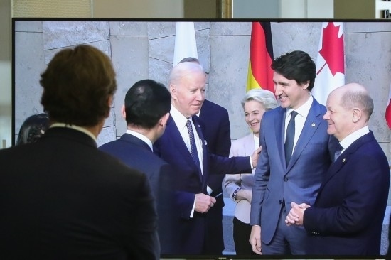 2022年3月24日，在比利時(shí)布魯塞爾的北約總部，一名男子觀看屏幕上美國總統(tǒng)拜登（右四）、歐盟委員會(huì)主席馮德萊恩（右三）、加拿大總理特魯多（右二）、德國總理朔爾茨（右一）出席七國集團(tuán)峰會(huì)合影儀式的畫面。新華社記者鄭煥松攝