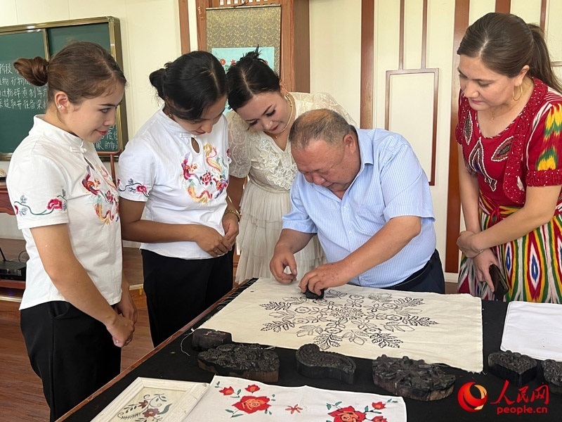 國(guó)家級(jí)非物質(zhì)文化遺產(chǎn)模戳印花布技藝傳承人吾吉阿西木?吾舒爾展示模戳印花布的制作過(guò)程。人民網(wǎng)記者 常雪梅攝