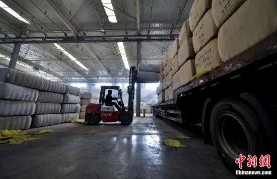 新疆喀什綜合保稅區(qū)，喀什啟路國際貿(mào)易有限公司的倉庫內(nèi)，工人正在裝載從塔吉克斯坦和烏茲別克斯坦進口的棉花。劉新攝