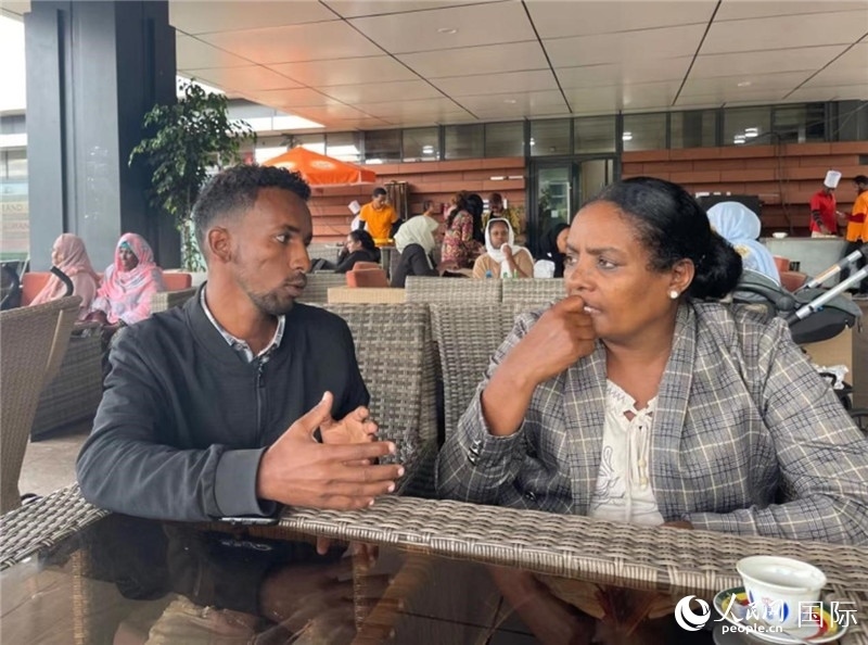 約漢斯（圖左）與德貝拉在友誼廣場咖啡廳交談。人民網(wǎng)記者 趙艷紅攝