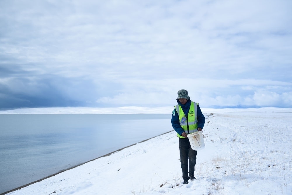 2021年10月20日，在青海省果洛藏族自治州瑪多縣扎陵湖鄉(xiāng)勒那村，三江源國(guó)家公園黃河源園區(qū)生態(tài)管護(hù)員在扎陵湖邊撿拾垃圾。新華社記者 張龍 攝
