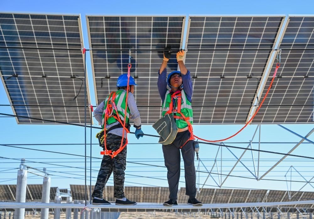 2023年7月22日，工人在位于內(nèi)蒙古杭錦旗庫(kù)布其沙漠億利生態(tài)示范區(qū)的蒙西基地庫(kù)布其200萬(wàn)千瓦光伏治沙項(xiàng)目工地安裝光伏板。新華社記者 劉磊 攝