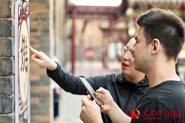 選手安德烈（俄羅斯）在老師指導(dǎo)下學(xué)習(xí)墻壁上張貼的生僻字。人民網(wǎng) 盧鵬宇攝