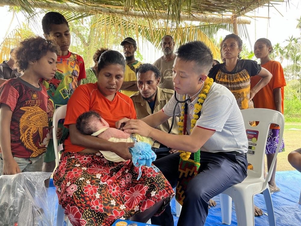 2023年8月5日，在巴布亞新幾內(nèi)亞中央省的一個村莊里，第12批援巴新中國醫(yī)療隊副隊長、新生兒科副主任醫(yī)師劉振球為當?shù)貗雰郝犜\檢查。新華社發(fā)（第12批援巴新中國醫(yī)療隊供圖）