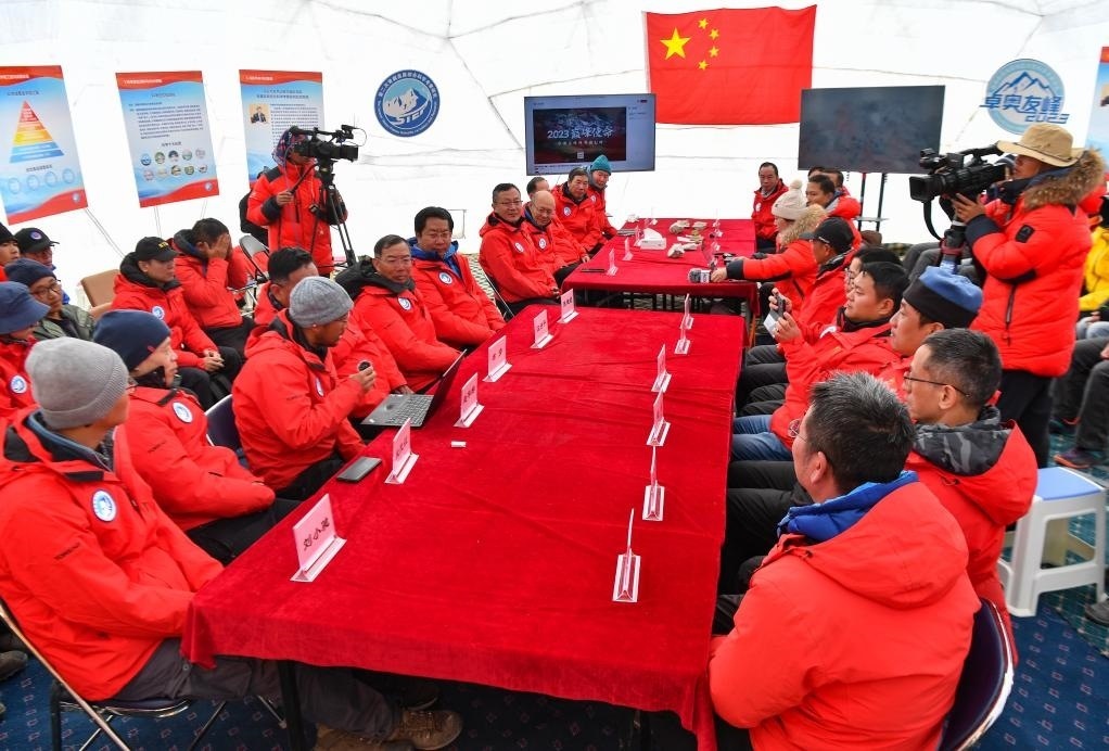 海拔4950米的卓奧友峰科考大本營，科考隊員趙華標(biāo)（手拿麥克風(fēng)看電腦者）在宣讀剛剛接收到的頂峰氣象觀測數(shù)據(jù)，這標(biāo)志著峰頂自動氣象站架設(shè)成功，成功傳回觀測數(shù)據(jù)（10月1日攝）。新華社記者晉美多吉 攝