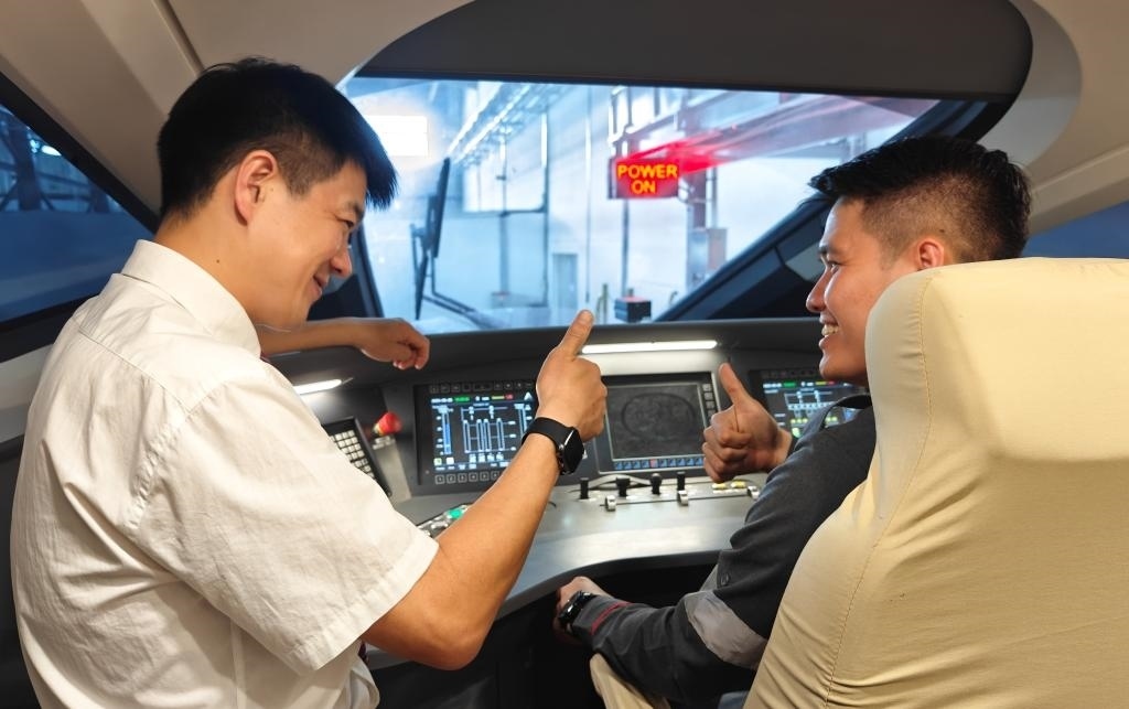 8月25日，在印度尼西亞萬隆的雅萬高鐵德卡魯爾動(dòng)車所內(nèi)，中國師傅穆振（左）在向印尼火車司機(jī)塞蒂亞萬講解動(dòng)車組出庫前的上電作業(yè)。