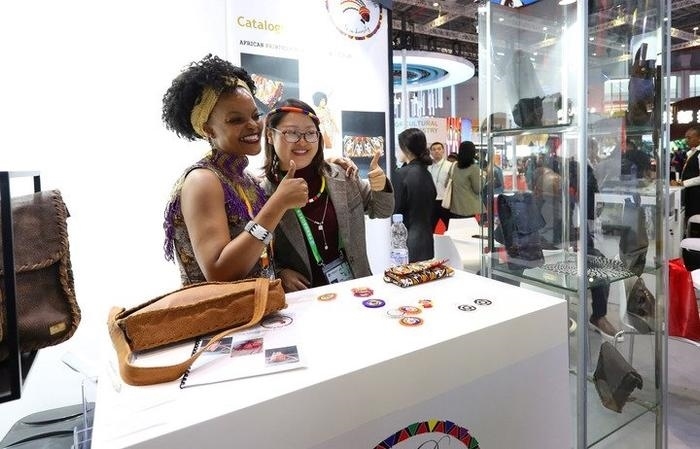 11月6日，一位參觀者（右）在第六屆進博會國家展南非展臺試戴傳統(tǒng)首飾。