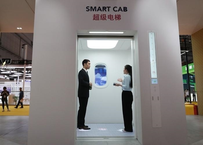 11月5日，工作人員（右）在第六屆進博會上向參觀者介紹奧的斯公司全新推出的超級電梯。