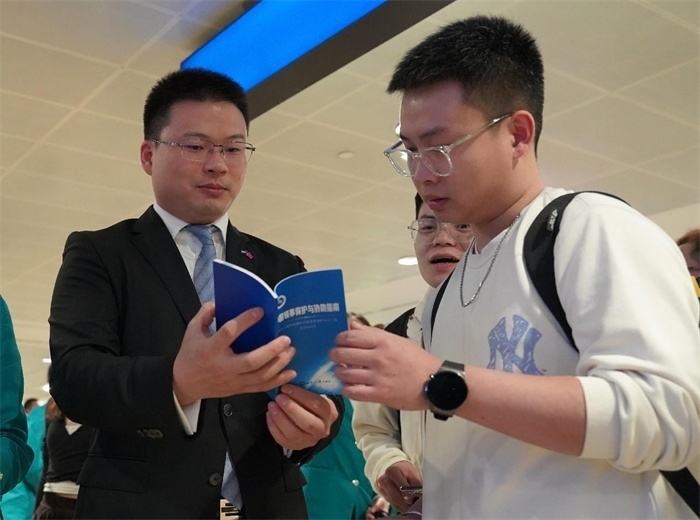 工作人員（左一）在發(fā)放《中國領(lǐng)事保護與協(xié)助指南》。 中國駐迪拜總領(lǐng)事館供圖