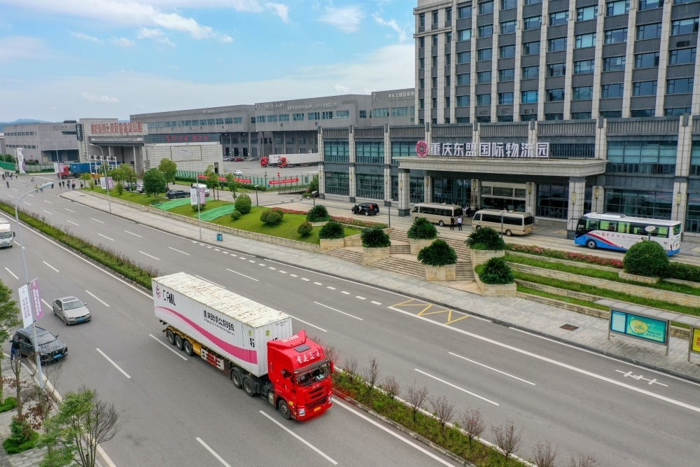 2023年10月11日，滿載筆記本電腦配件、發(fā)電機組件等產(chǎn)品的西部陸海新通道跨境公路班車從重慶南彭公路保稅物流中心駛出，將途經(jīng)廣西憑祥，直達越南（無人機照片）。新華社記者 黃偉 攝