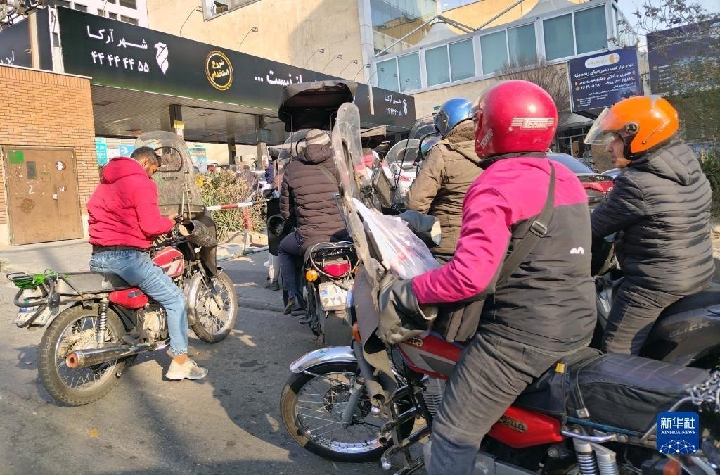 12月18日，摩托車在伊朗首都德黑蘭的一家加油站外等待加油。新華社記者 沙達提 攝