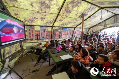 12月22日，在積石山縣大河家鎮(zhèn)大河村安置點(diǎn)，陸軍76集團(tuán)軍某旅搭建的“臨時(shí)學(xué)?！眱?nèi)，小朋友正在看動(dòng)畫片。人民網(wǎng)記者 翁奇羽攝