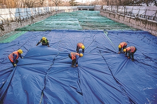 1月3日，房山區(qū)東風街道，工人正在修復的河道內給混凝土鋪設保溫布。