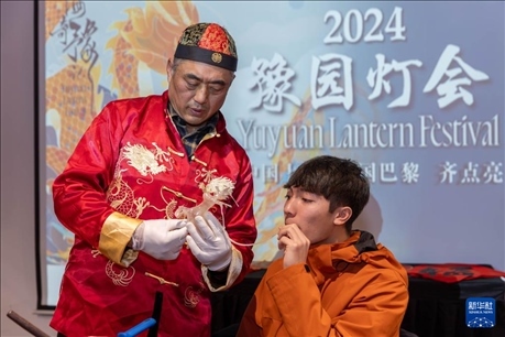 1月28日，在上海豫園舉行的民俗活動(dòng)上，美國(guó)馬斯卡廷中學(xué)學(xué)生在非遺傳承人的指導(dǎo)下吹糖偶。 新華社記者 王翔 攝