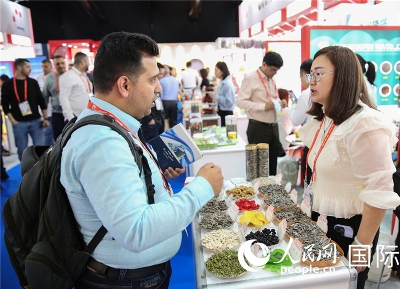 圖為一家中國干果參展企業(yè)代表與采購商洽談。人民網(wǎng) 塔里克·易卜拉欣攝