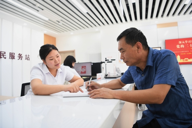 2023年5月23日，河北雄安新區(qū)容東片區(qū)南文營社區(qū)居民（右）在社區(qū)便民服務站辦理業(yè)務。