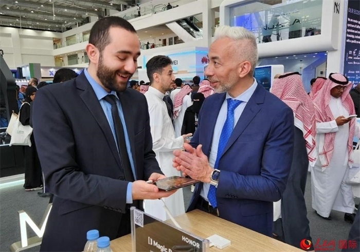 兩名觀眾在榮耀手機(jī)展臺(tái)前交流。人民網(wǎng)記者 管克江攝