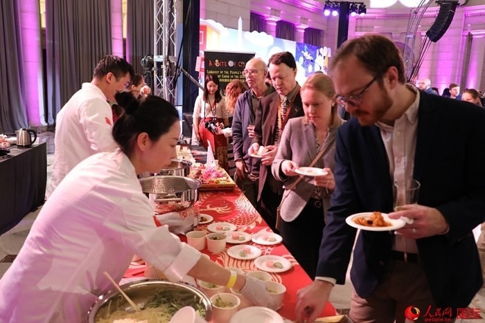 當?shù)貢r間3月7日晚，華盛頓聯(lián)合車站廣場舉行駐美使團“使館主廚挑戰(zhàn)賽”。圖為當?shù)孛癖娫谥袊古_前體驗中國美食。人民網(wǎng)記者 李志偉攝