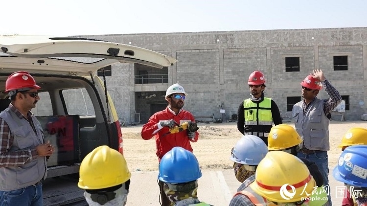 穆薩瓦爾(圖中紅衣人）現(xiàn)場演示工具操作規(guī)范。人民網(wǎng)記者 管克江攝