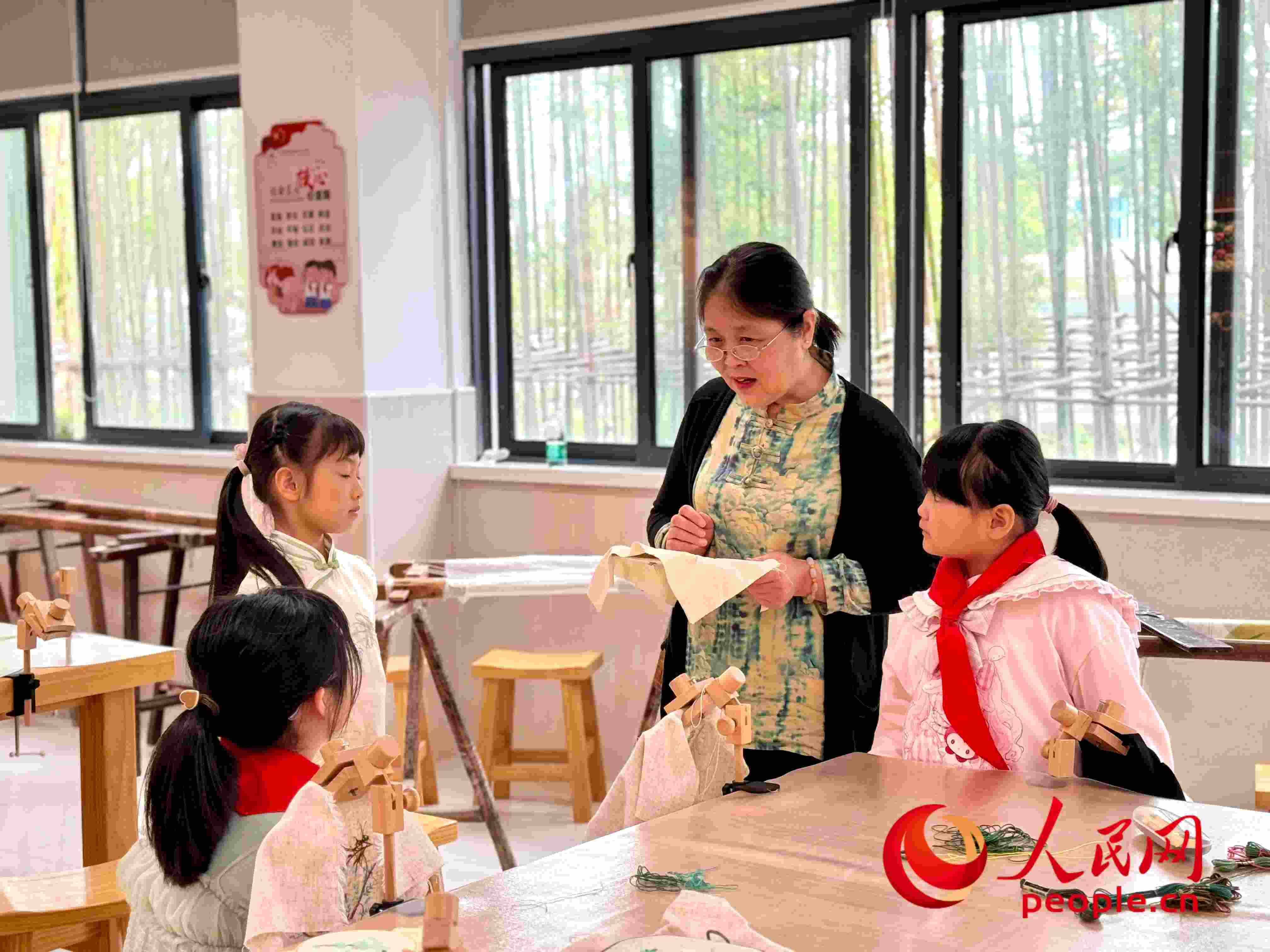 顧建珍（左三）在教孩子們刺繡知識。人民網(wǎng) 周靜圓攝