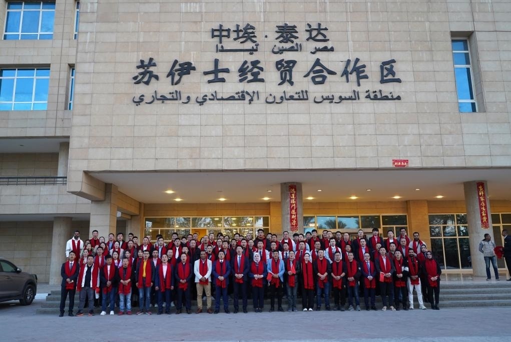 2024年2月11日，在位于埃及蘇伊士省的中?！ぬ┻_(dá)蘇伊士經(jīng)貿(mào)合作區(qū)，中埃員工在合作區(qū)辦公大樓前合影拜年。新華社發(fā)（泰達(dá)合作區(qū)供圖）