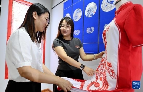 5月31日，在衡水市阜城縣一家剪紙工作室，游客在觀賞帶有剪紙?jiān)氐钠炫邸? width=