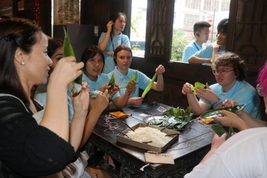 6月9日，美國青年代表在重慶永川松溉古鎮(zhèn)體驗(yàn)包粽子。新華社記者 周思宇 攝