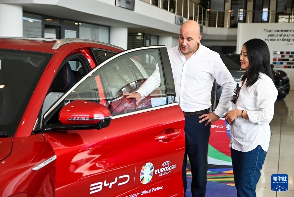 2024年5月29日，在馬耳他比爾基卡拉，馬耳他哈桑-扎米特汽車公司首席執(zhí)行官德古阿拉（左）介紹一輛比亞迪純電動(dòng)汽車。新華社發(fā)（喬納森·博格 攝）