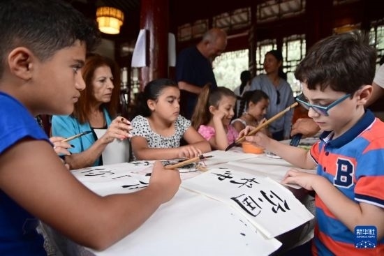 7月4日，在馬耳他桑塔露琪亞市的中國古典園林“靜園”，人們體驗(yàn)中國書法。新華社發(fā)（喬納森·博格 攝）