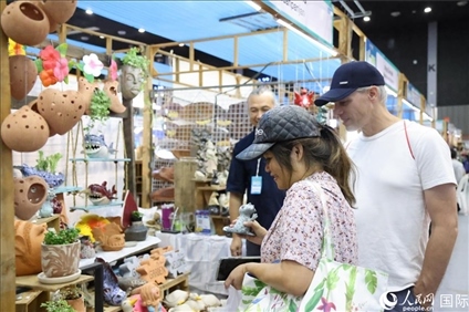 游客在蘭納博覽會特色展位上選購工藝品。人民網(wǎng)記者楊一攝