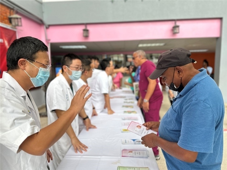 援圭醫(yī)療隊(duì)隊(duì)員們?cè)趩?dòng)儀式上為當(dāng)?shù)孛癖姺职l(fā)宣傳手冊(cè)。中國援助圭亞那醫(yī)療隊(duì)供圖