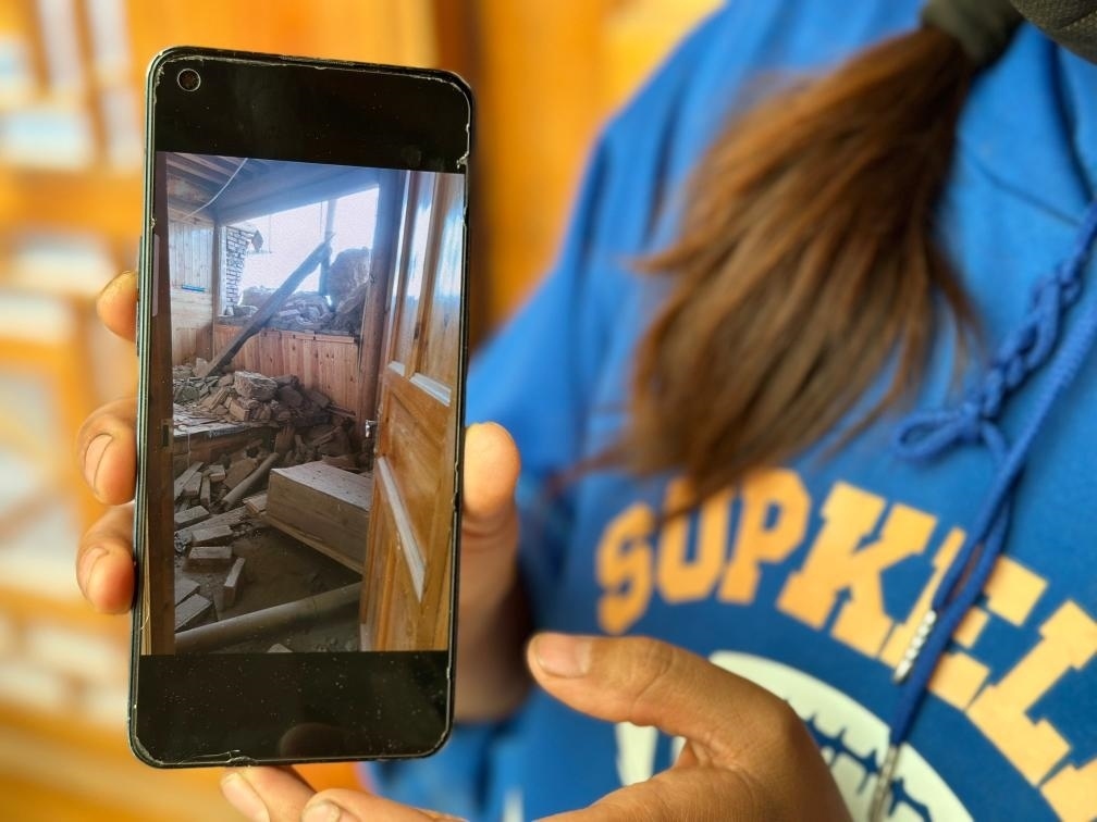 圖為7月17日拉毛東智在手機(jī)上找出地震后房屋受損的照片。新華社記者 張子琪 攝