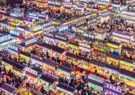 2024年4月21日，人們?cè)诤颖笔≌h小商品夜市品嘗美食（無(wú)人機(jī)照片）。新華社發(fā)（武志偉 攝）