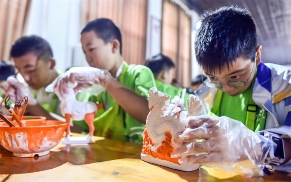 小朋友們在洛陽市孟津區(qū)朝陽鎮(zhèn)南石山村體驗(yàn)唐三彩素胎施釉技藝。圖片來源：視覺中國