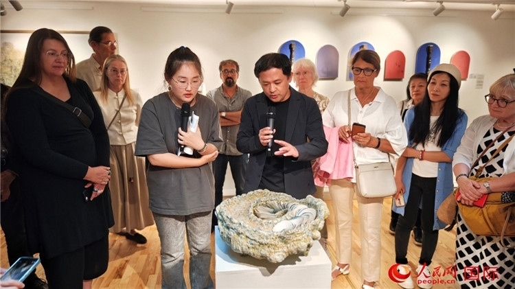 參展人、景德鎮(zhèn)陶瓷大學(xué)設(shè)計藝術(shù)學(xué)院副院長余劍峰（中）向來賓介紹參展作品。人民網(wǎng)記者 殷淼攝