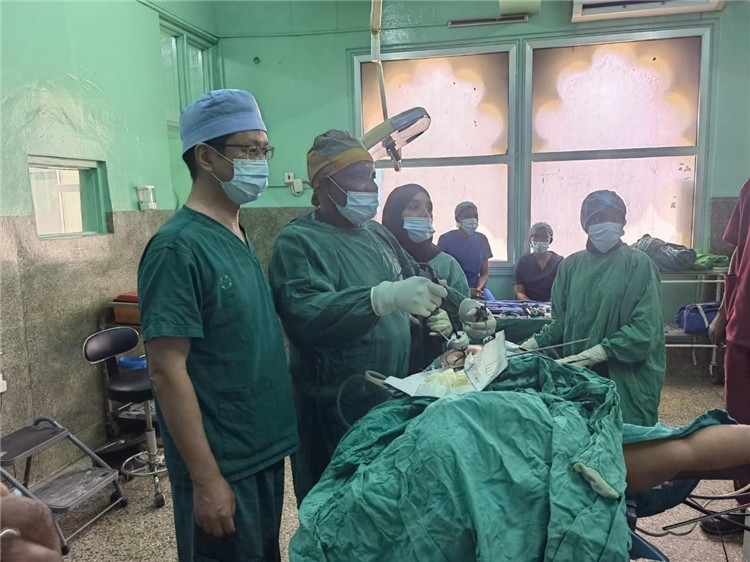 隊長蔣國慶（左一）關(guān)注當(dāng)?shù)蒯t(yī)生手術(shù)情況。中國援桑醫(yī)療隊供圖