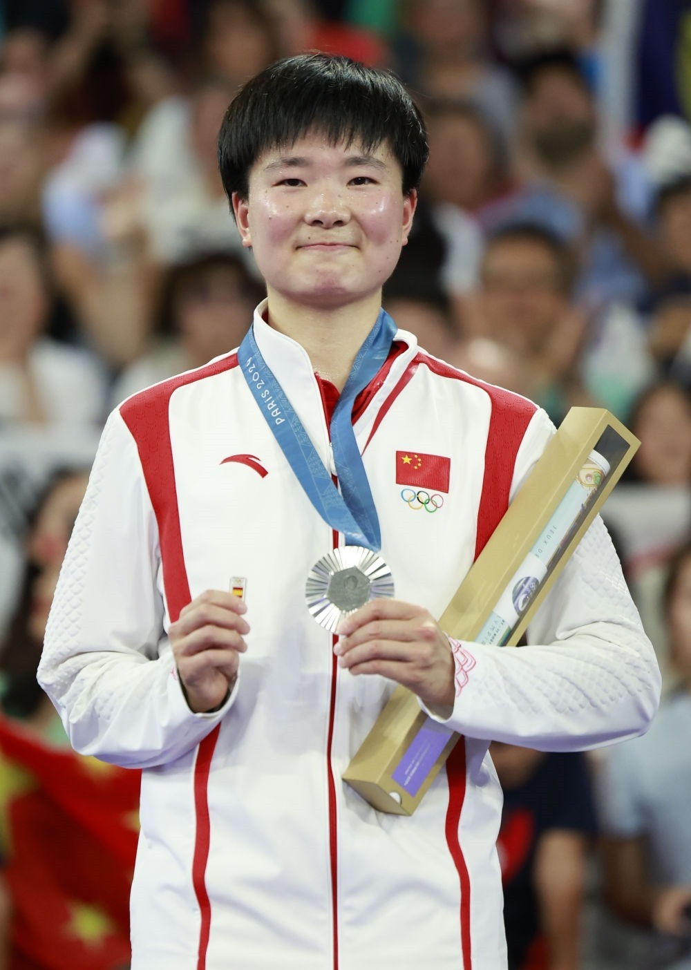 巴黎奧運會羽毛球女子單打亞軍、中國選手何冰嬌在頒獎儀式上一手握著銀牌，一手握著西班牙奧委會徽章（2024年8月5日攝）。新華社記者 任正來 攝