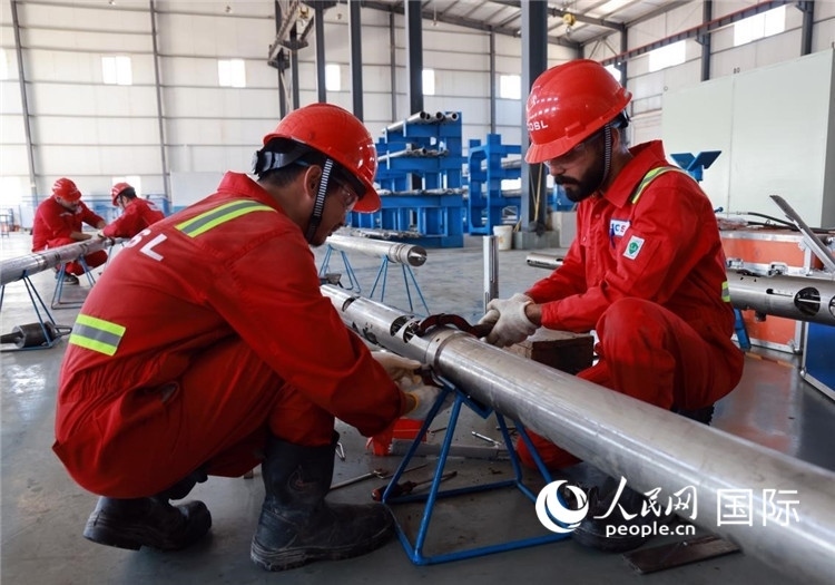中伊員工共同在檢修鉆井設(shè)備。人民網(wǎng)記者管克江攝