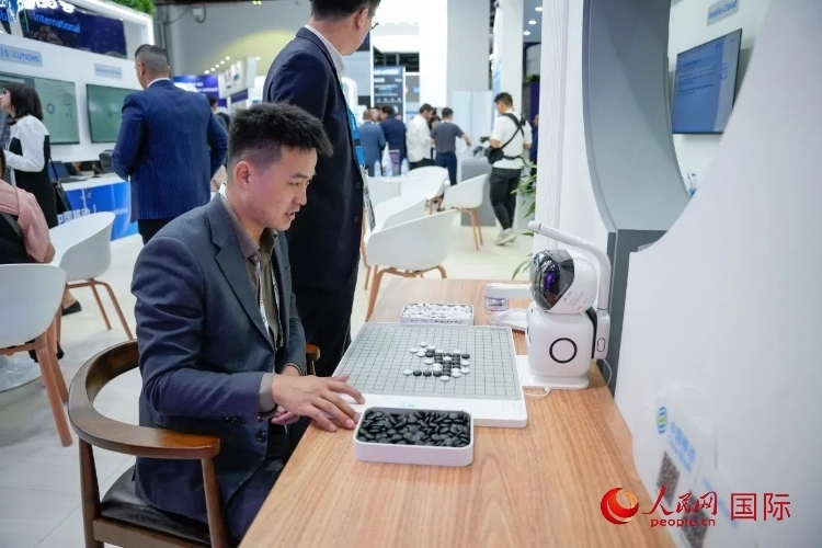 觀眾在中國移動(dòng)國際有限公司展臺(tái)體驗(yàn)智慧圍棋機(jī)器人。人民網(wǎng) 塔里克·易卜拉欣攝
